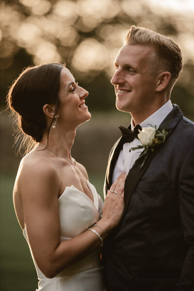 bride and groom laughing at each other during golden hour portraits