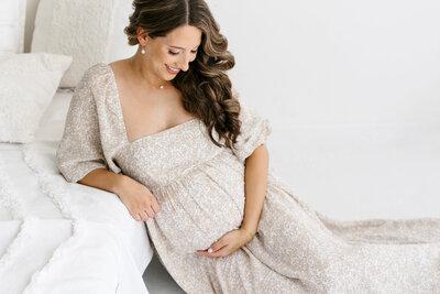 Pregnant mother in photography studio holding her belly