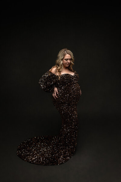 Stunning mother-to-be wearing a beautiful gold and black sequenced maternity gown.
