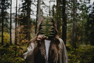 Woman holding a fern leaf in the forest
