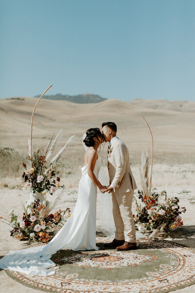 Couple standing at ceremony arch at their boho ranch wedding