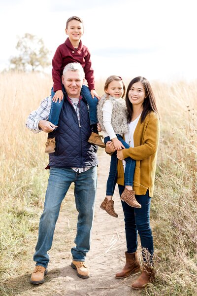 Family of four pose in a field outside of Edina Minnesota for Christmas Card family photo session.