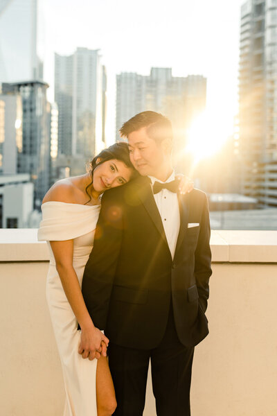 Bride in white dress holding hands with groom in black suit in front of Charlotte skyline by Charlotte wedding photographer, Stephanie Bailey Photography.