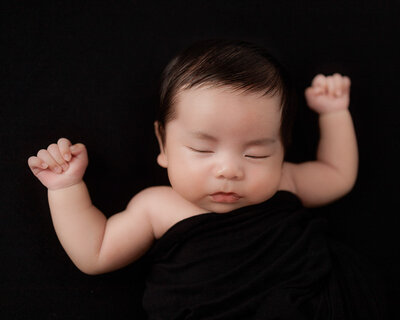 baby boy covered in black fabric sleeping