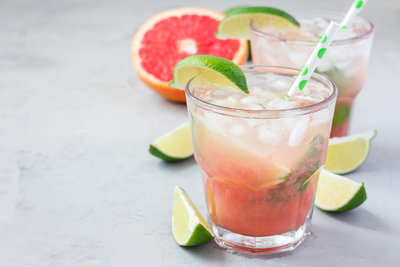 2 specialty cocktails garnished with grapefruit & lime