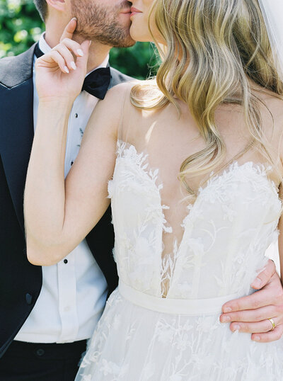 Close up of the Bride and Groom kissing. The bride has her hand up romantically to the groom's face.
