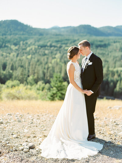 bride and groom facing each other and standing with mountains in the background