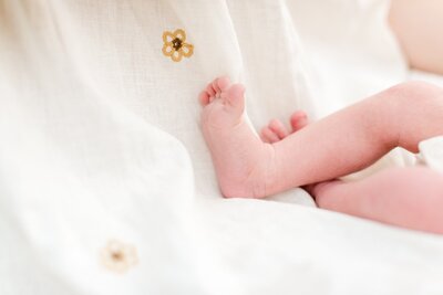 Closeup portrait of newborn's feet against mother's dress for family newborn photography session in