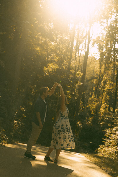 Man and woman romantically spin around, laughing in the middle of a  flowery field