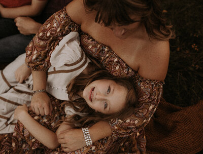 young girl laying in her mother's lap.