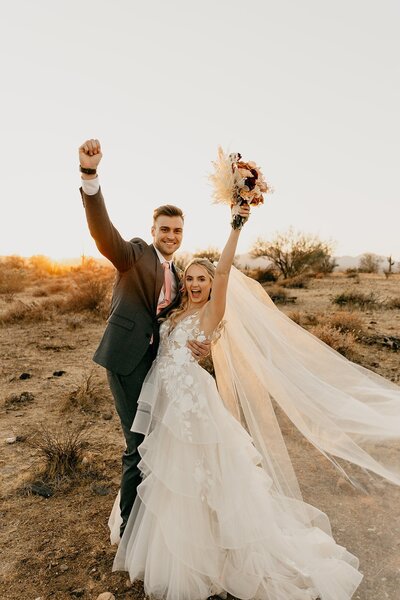 Couple cheering in wedding attire in the Phoenix desert
