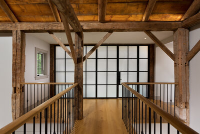 Wooded hallway looking at a glass window pane wall into a gym 