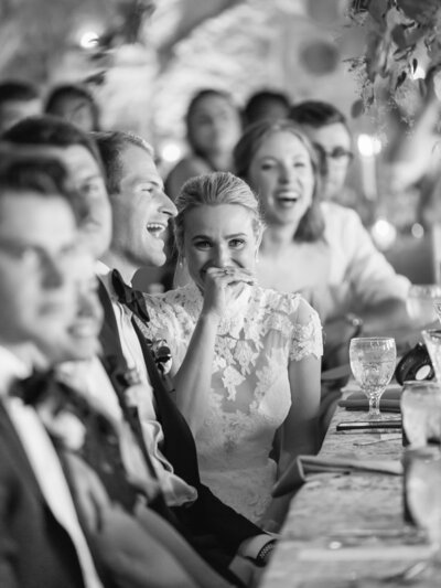 Bride and groom laughing during a speech at their reception