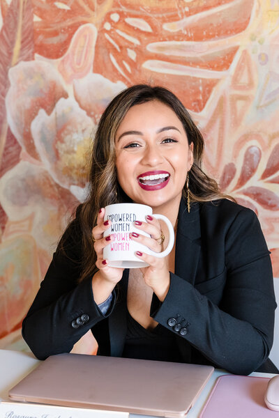 brand photo of a coach with an on-brand mug in her hands, smiling