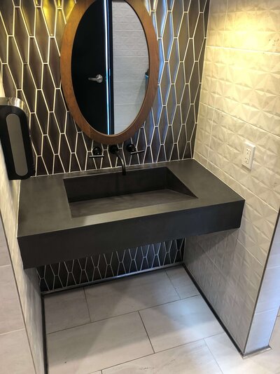 Single ADA-compliant  basin concrete ramp sink in boutique hotel in carbon concrete
