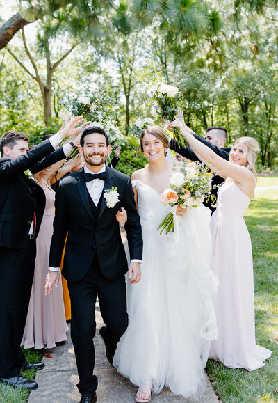 Bride and Groom walking through a tunnel of bridal  parties arms raised