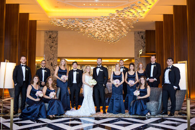 An indoor bridal party photo under a modern chandelier at  Ritz Carlton hotel in Chicago.