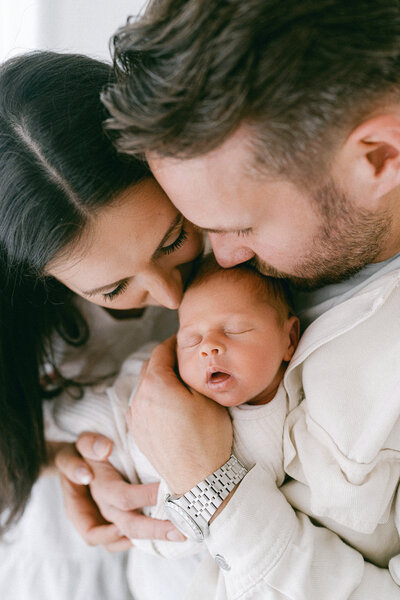 New parents kissing their newborn baby boy on a photoshoot