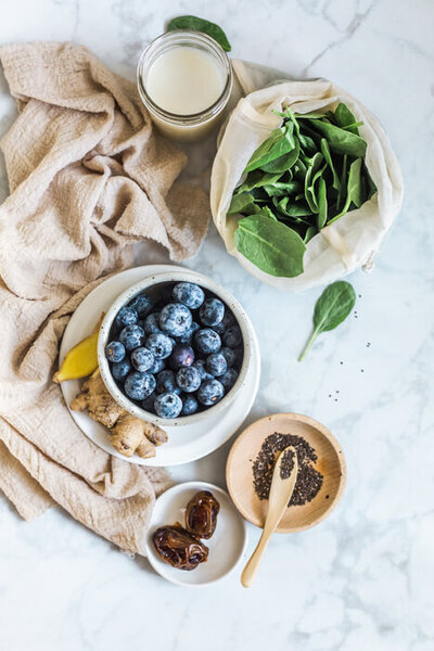 Picture of blueberries, spinach and dates on a counter space. 
