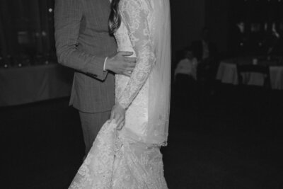 Black and white photo of the bride and groom slow dancing at their wedding reception