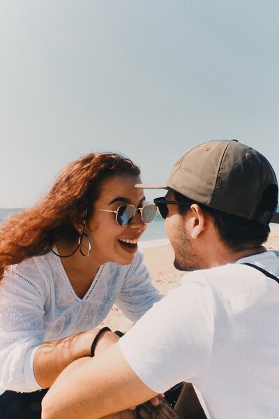 A woman on a beach smiling at her partner. Representing that joy that can grow after working together in couples therapy in Manhattan. With marriage counseling you can start to truly enjoy your relationship again.