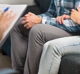 A couple sits close to one another as a therapist with a clipboard speaks. This could represent what communication therapy for couples in Florida might look like. Couples communication therapy can help you strengthen your relationship. Contact Idit Sharoni today.