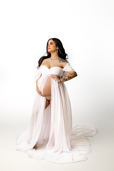 expectant mom in studio maternity session dressed in a white off shoulder  maternity dress 