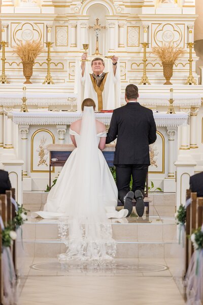 Bride and groom kneel for communion in Catholic traditional wedding  ceremony