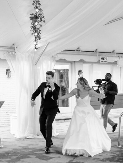 Wedding couple being introduced into reception, while being followed by virginia beach wedding videographer with camera.