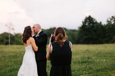 a photo of a wedding photographer taking photos of a bride and groom on their wedding day in a field