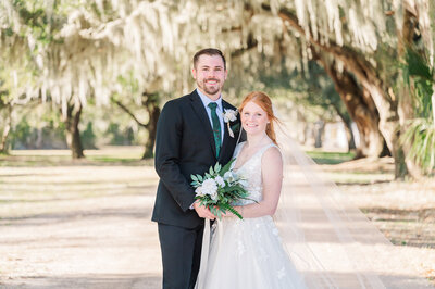 A happy couple under Spanish moss trees during their destination wedding in Savannah by destination wedding photographer, JoLynn Photography