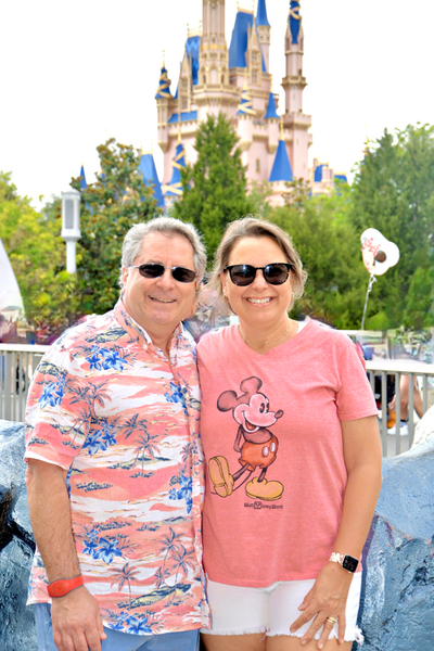 Happy middle-aged man and woman in front of Cinderella Castle at Magic Kingdom at Disney World