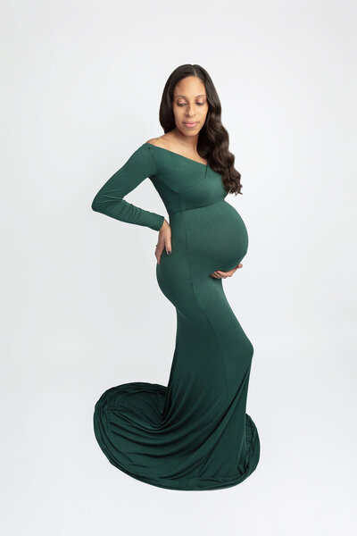studio maternity portrait of a beautiful african american expecting mama wearing a long green maternity gown and