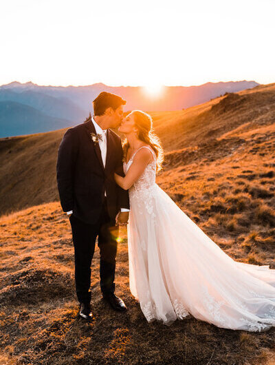 a bride and groom kiss right as the sun sets behind the olympic mountains on hurricane ridge on their elopement day