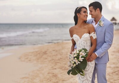 Groom hugging bride on beach after wedding in Riviera Maya