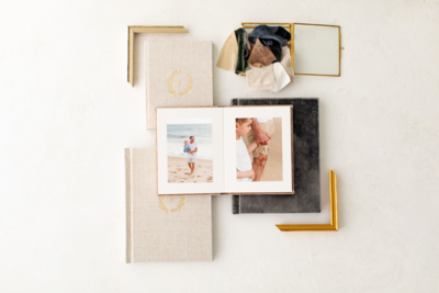 two photo albums with two frame corners and fabric swatches surrounding them.  On top sits a 4x6 print of a husband and wife holding hands and smiling at each other.