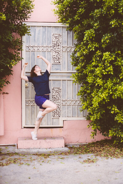 Michelle-Marie Gilkeson  in a dance pose  on a step in front of a residence