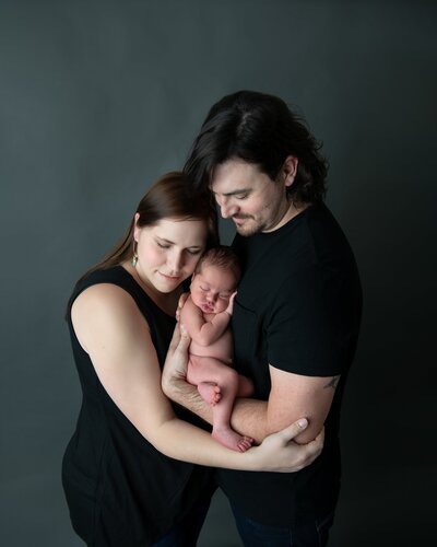 family of three holding newborn baby