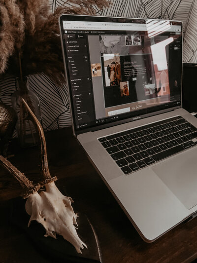 Laptop on Design Studios desk featuring a showit website design custom made for a  photographer