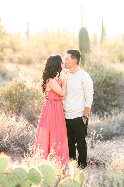 engaged couple kissing in desert brush