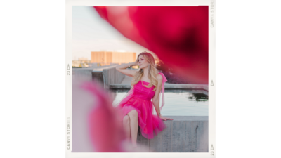 Woman styled as Barbie poses in Downtown Houston Texas in a pink tulle dress framed by balloons