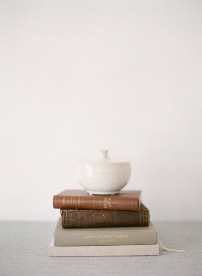 A stack of books with a white dish on top.