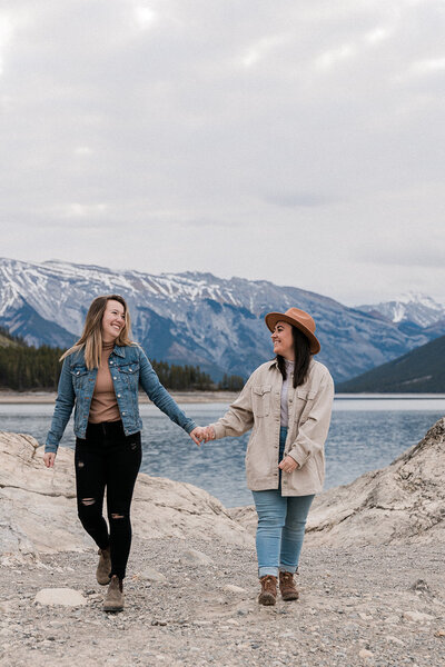 Couple holding hands laughing in the rocky mountains