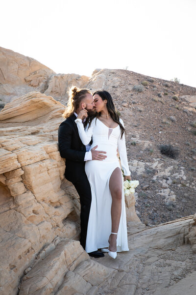 An Austin-based wedding photographer captures a beautiful moment of a bride and groom sharing an intimate kiss on a rock in the desert.