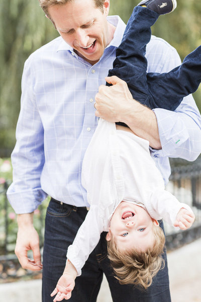 dad holding son upside down and child is laughing