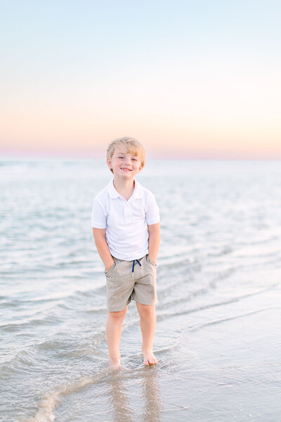 Boy standing on beach at sunset