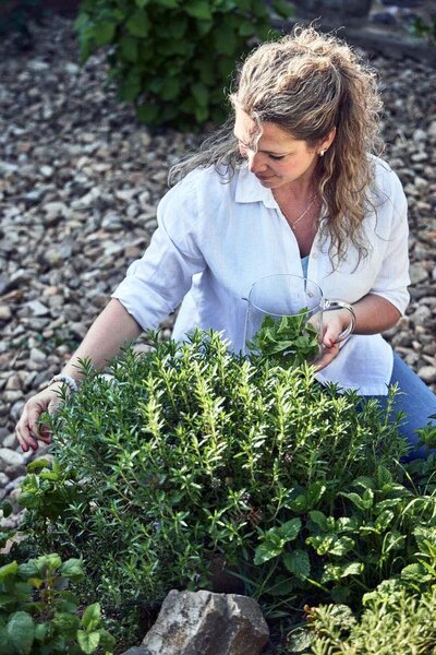 Sarka collecting fresh herbs for tea in her garden