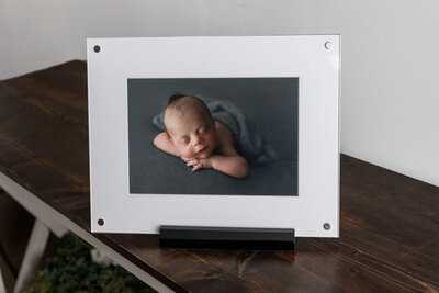 matted photo of a newborn baby boy in a display frame on a wooden table