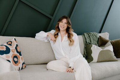 A portrait of Haley Adele a waikato and bay of plenty wedding photographer sitting on a chair and posing for the camera