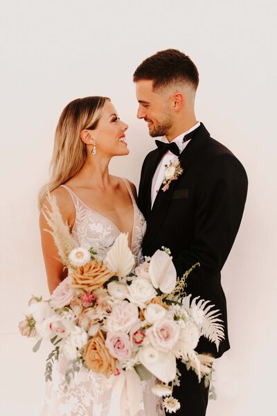 Couple Posing with Orchid Filled Bouquet - Bre & Chris | Converted Basketball Court Wedding – Featured in Brides Magazine